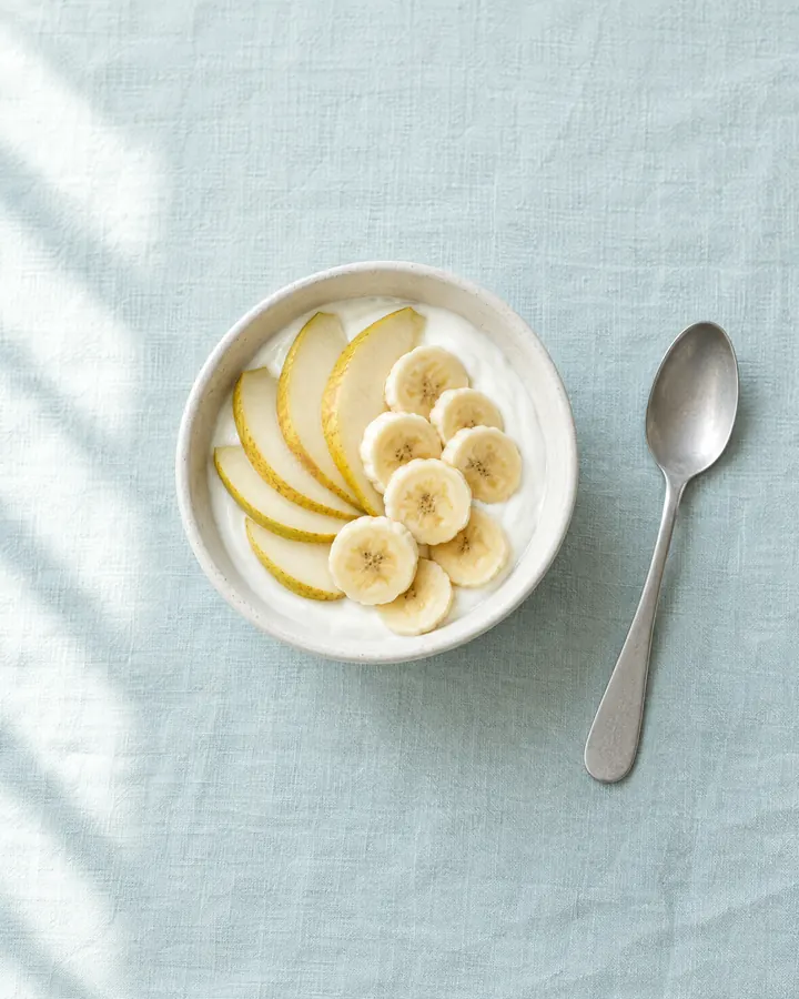 Iogurte natural com pera e banana às rodelas.